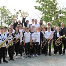 Die Musikerinnen und Musiker stehen nebeneinander, sie halten ihre Instrumente in der Hand und schauen freundlich in die Kamera. ©Burgmusikschule Querfurt